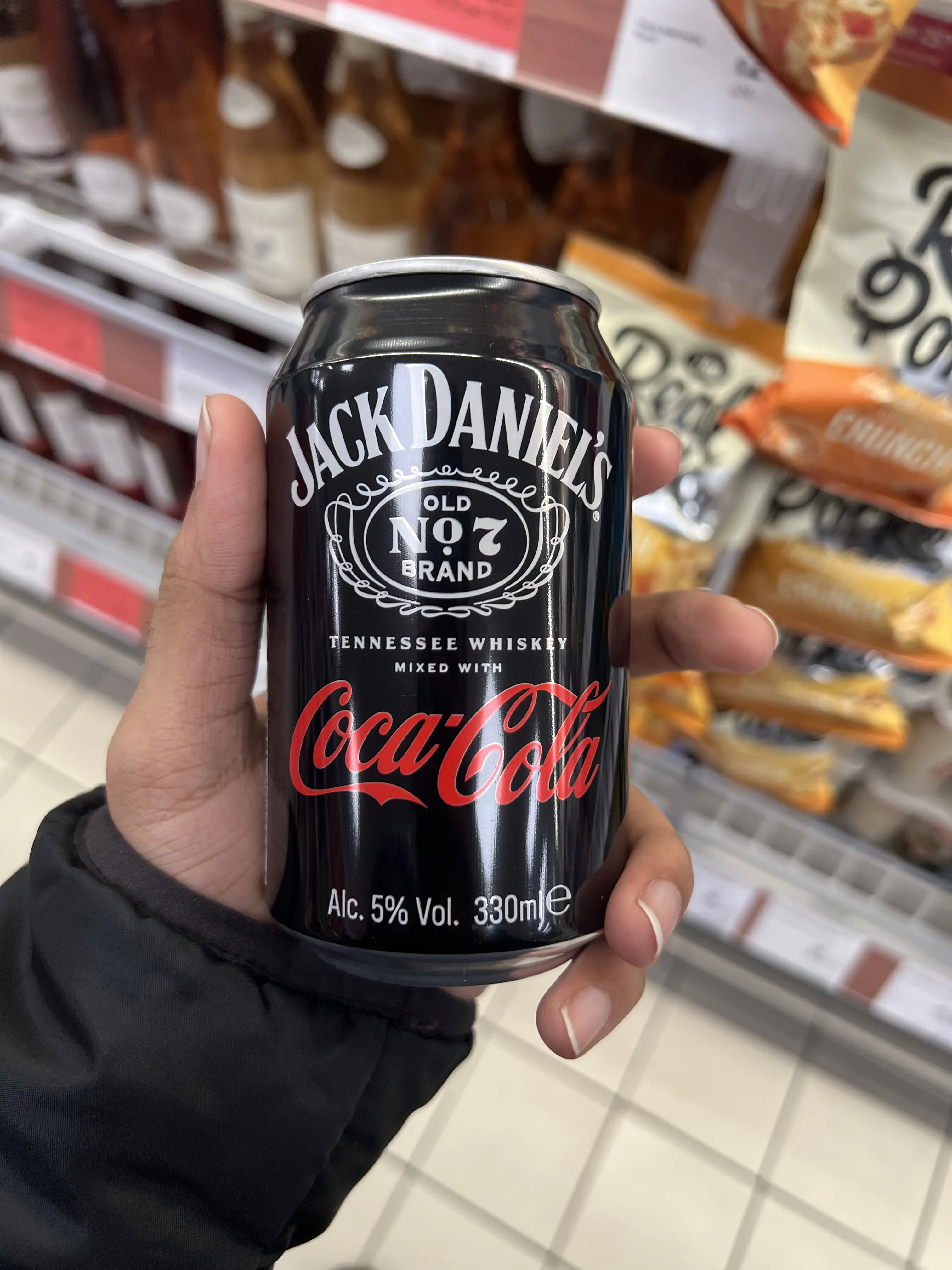 A guy holding a can of Jack Daniels Cola